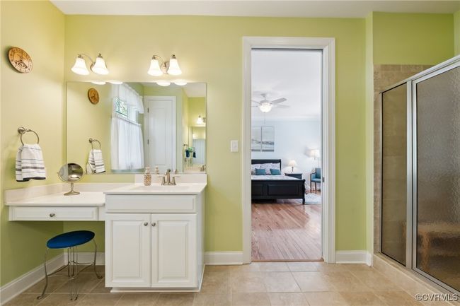 Primary bathroom has dual vanities one on each side. This vanity offers a makeup counter. Framed tiled shower to the right. | Image 19