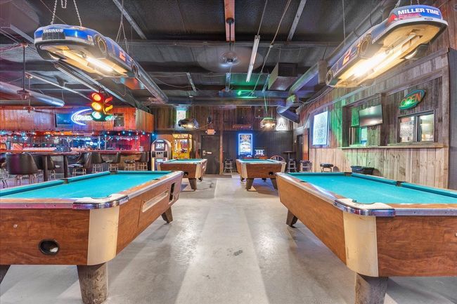 Recreation room with billiards table, concrete flooring, a community bar, and wood walls | Image 6
