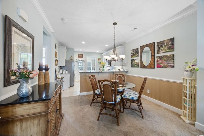 Dining room featuring crown molding, light carpet, wainscoting, a textured ceiling, and a chandelier | Image 9