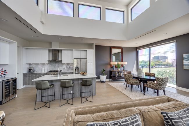 Kitchen featuring a kitchen breakfast bar, beverage cooler, modern cabinets, high quality fridge, and white cabinets | Image 17