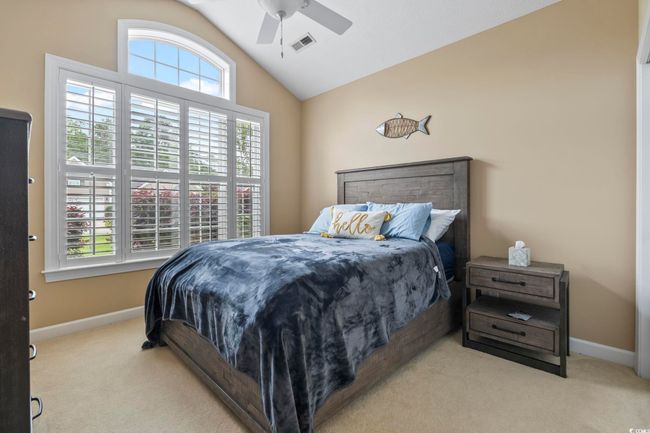 Bedroom featuring lofted ceiling, visible vents, carpet flooring, and baseboards | Image 16