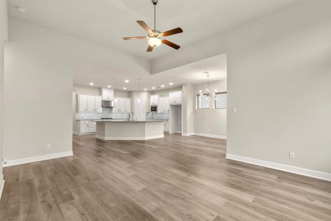 Unfurnished living room featuring a chandelier, light wood-style floors, recessed lighting, ceiling fan, and baseboards | Image 13