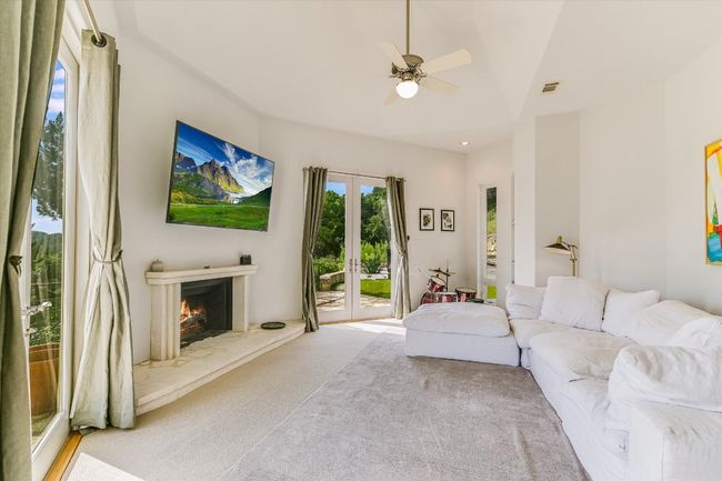 Carpeted living area with ceiling fan and a warm lit fireplace | Image 15