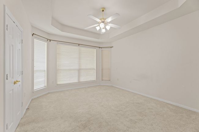 Unfurnished bedroom featuring carpet flooring, a tray ceiling, and a ceiling fan | Image 27