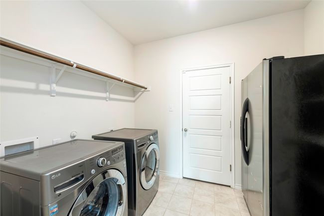 Laundry area featuring light tile patterned flooring and washing machine and dryer | Image 30