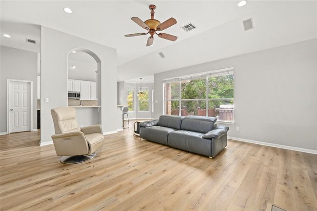 Living area with light wood finished floors, a ceiling fan, visible vents, and a wealth of natural light | Image 6