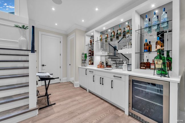 Bar featuring wet bar, beverage cooler, light wood-style floors, and stairs | Image 17