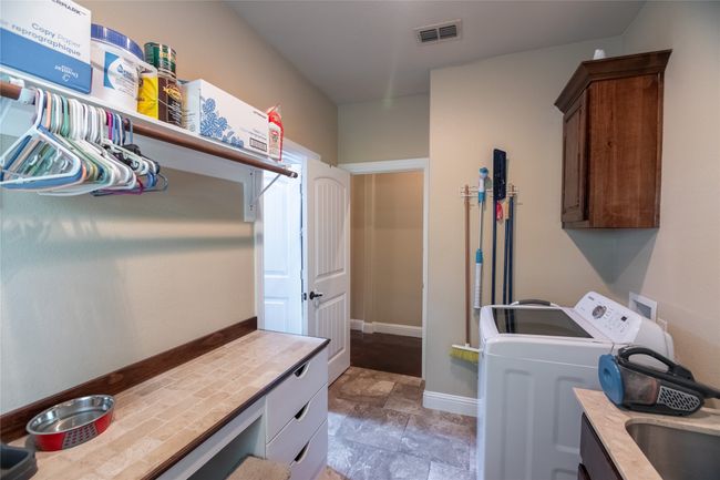 Laundry area with cabinet space, washing machine and dryer, stone finish floors, and baseboards | Image 29