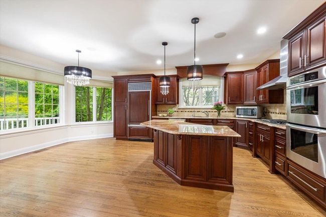 Kitchen with appliances with stainless steel finishes, a chandelier, a kitchen island, backsplash, and recessed lighting | Image 9