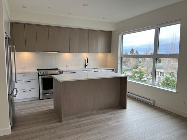 Kitchen featuring stainless steel appliances, a baseboard heating unit, modern cabinets, light countertops, and tasteful backsplash | Image 9