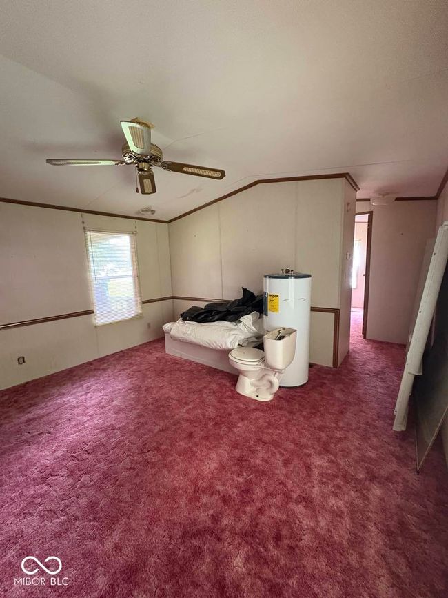 bedroom with water heater, carpet floors, a ceiling fan, and vaulted ceiling | Image 15
