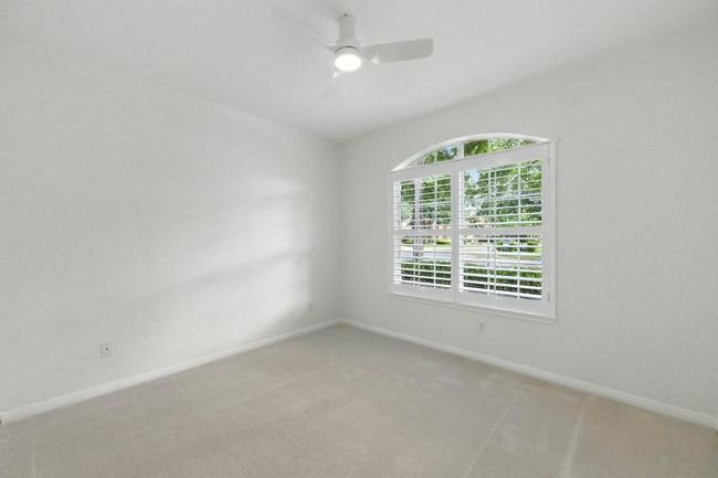 Secondary bedroom with natural light, simple shutters, new carpet and fan. | Image 26