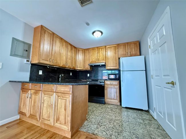 Kitchen with freestanding refrigerator, stainless steel electric stove, under cabinet range hood, a peninsula, and tasteful backsplash | Image 10