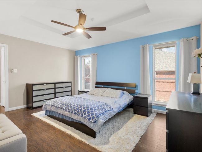 Bedroom with a raised ceiling, wood finished floors, and ceiling fan | Image 15