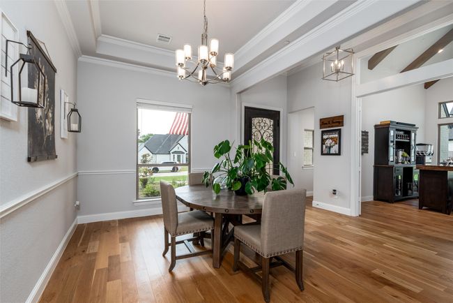 Dining room with a chandelier, light wood finished floors, ornamental molding, and baseboards | Image 6