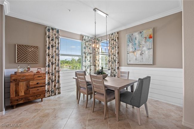 Dining area with an inviting chandelier, wood walls, crown molding, and a wainscoted wall | Image 22