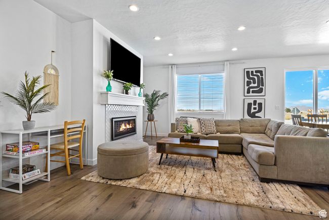 Living area featuring hardwood / wood-style flooring, recessed lighting, a textured ceiling, and a glass covered fireplace | Image 22