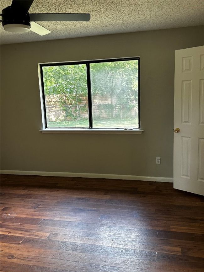 Empty room featuring dark wood-style floors, a textured ceiling, and a ceiling fan | Image 12