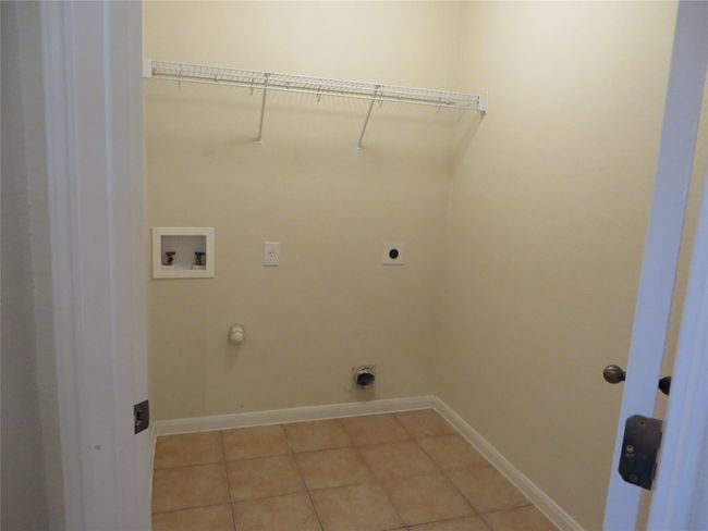 Washroom with hookup for a washing machine, electric dryer hookup, gas dryer hookup, light tile patterned floors, and baseboards | Image 5