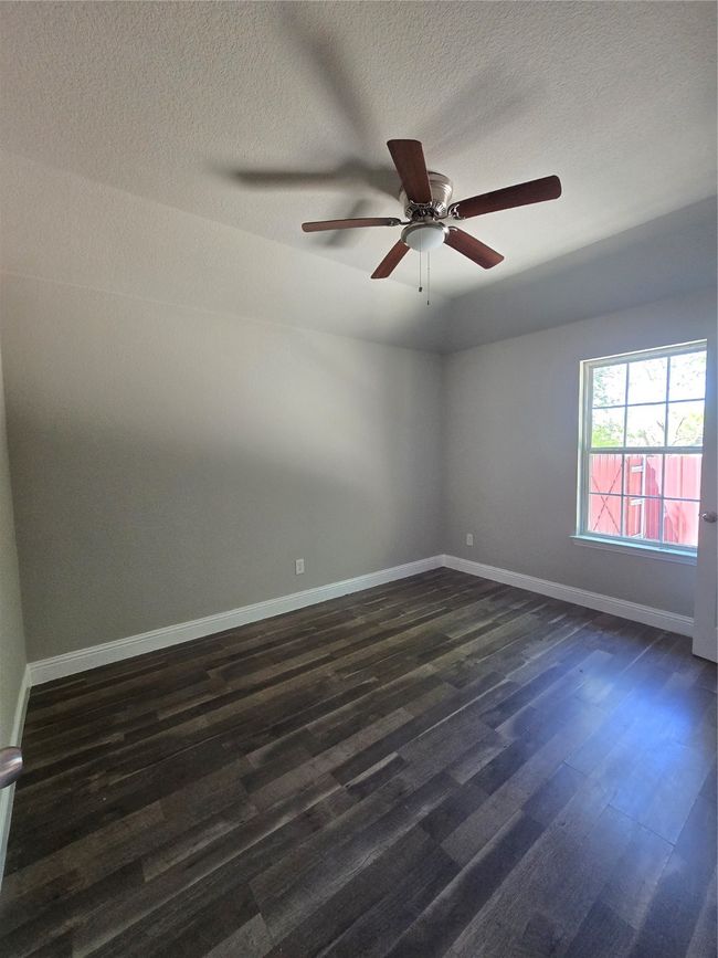 Empty room featuring a ceiling fan, a textured ceiling, baseboards, and dark wood-style floors | Image 10