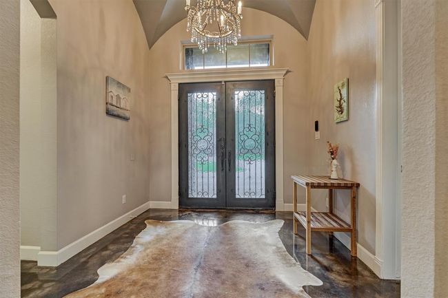 This view shows the rich wood-stained double glass doors, beautifully detailed with wrought iron accents that add a touch of timeless elegance and character to the entry. | Image 8