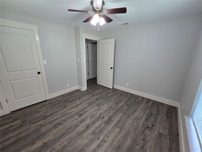 Unfurnished bedroom with dark wood finished floors and a ceiling fan | Image 10