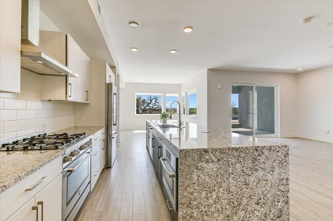 Kitchen with a kitchen island with sink, a sink, tasteful backsplash, appliances with stainless steel finishes, and wall chimney range hood | Image 8