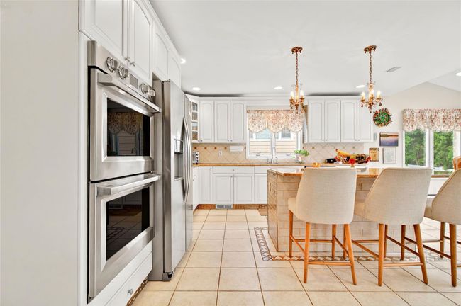 Kitchen with healthy amount of natural light, backsplash, a breakfast bar, appliances with stainless steel finishes, and recessed lighting | Image 20