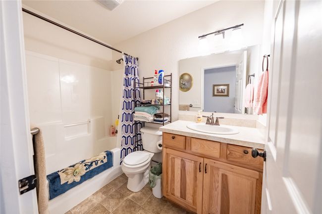 Full bath featuring vanity, shower / bath combination with curtain, toilet, and tile patterned floors | Image 15
