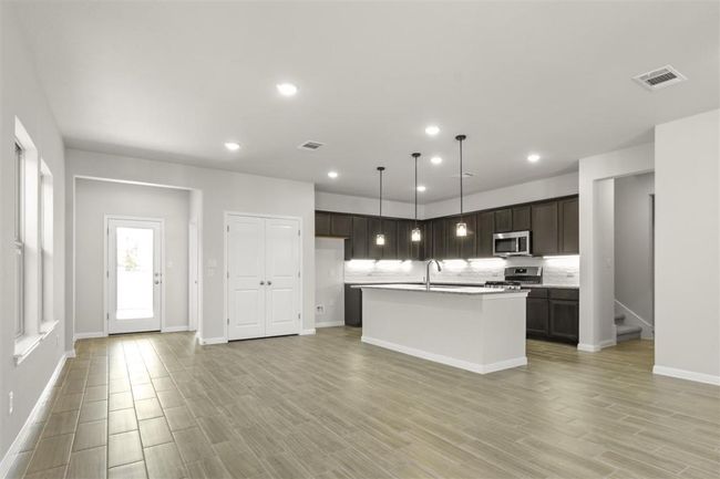 Kitchen with stainless steel appliances, light wood finished floors, and visible vents | Image 11