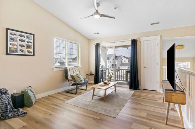 Sitting room with light wood-style flooring, ceiling fan, lofted ceiling, and visible vents | Image 6