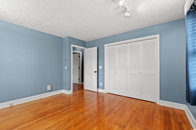 Unfurnished bedroom with light wood-style floors, a textured ceiling, and baseboards | Image 12