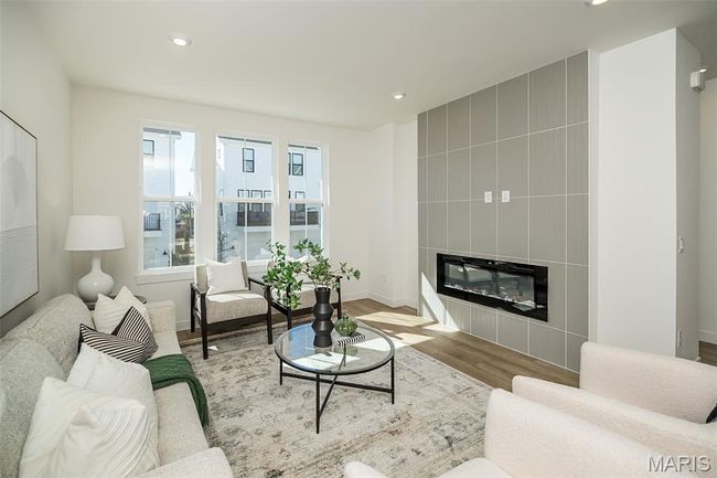 Living area with wood finished floors, recessed lighting, and a tiled fireplace | Image 14