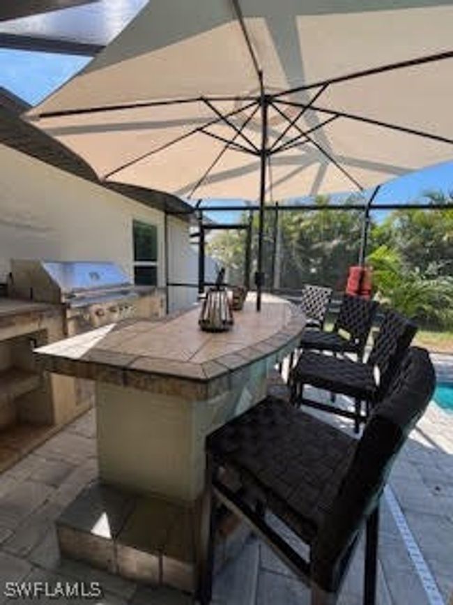 View of patio with an outdoor pool, outdoor dry bar, area for grilling, and glass enclosure | Image 30