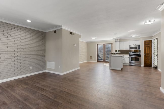 Unfurnished living room featuring crown molding, visible vents, and brick wall | Image 9