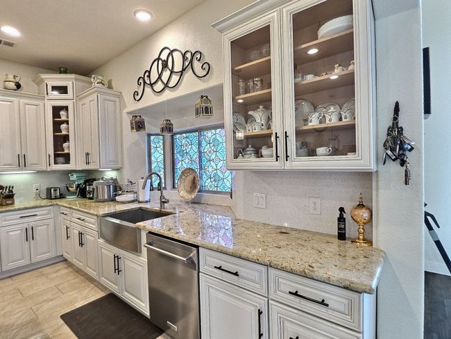 Kitchen featuring a sink, stainless steel dishwasher, light stone counters, and white cabinets | Image 14