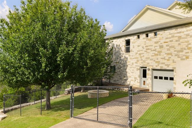 View of home's exterior featuring an attached garage, stone siding, driveway, and a gate | Image 39
