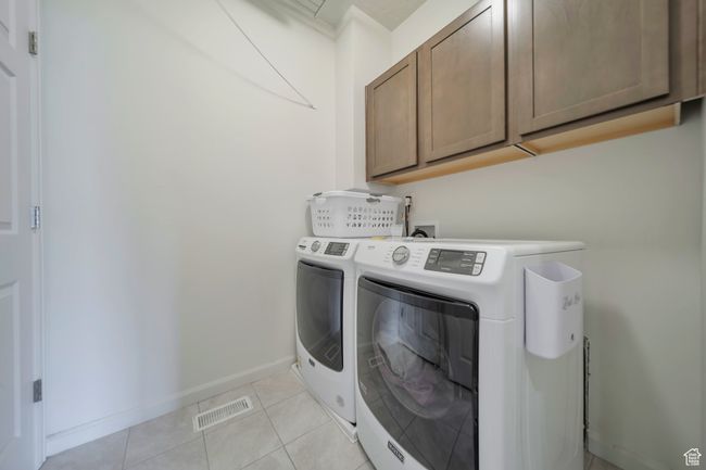 Laundry area with cabinet space, visible vents, light tile patterned floors, and separate washer and dryer | Image 15