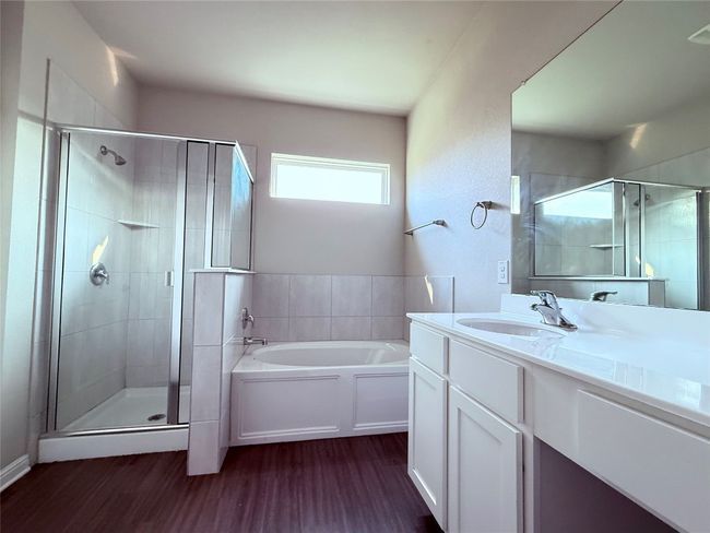 Bathroom featuring a bath, a stall shower, vanity, and wood finished floors | Image 8