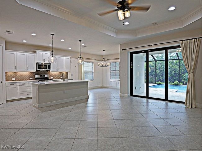 Kitchen with appliances with stainless steel finishes, crown molding, a sink, backsplash, and light tile patterned flooring | Image 4