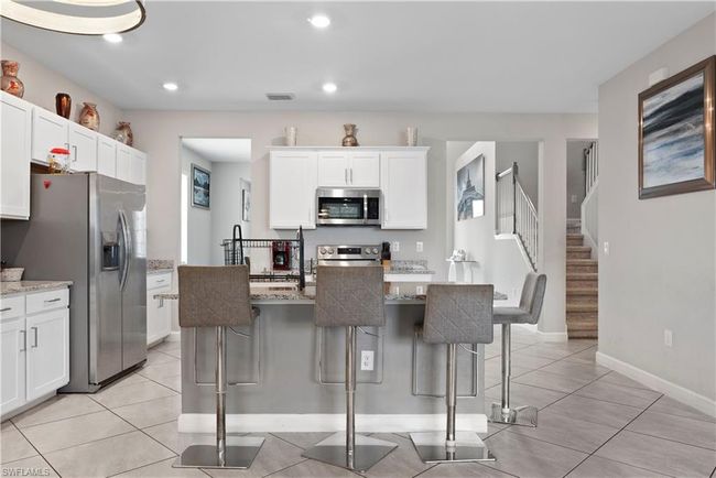 Kitchen featuring visible vents, stainless steel appliances, a kitchen breakfast bar, and light tile patterned floors | Image 13