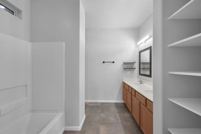 The practical and efficient primary bath features abundant linen shelving, dual sinks, tub/shower combo a simple clean aesthetic. | Image 19