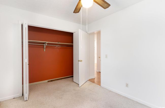 Unfurnished bedroom featuring light colored carpet, ceiling fan, and a closet | Image 20
