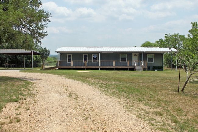 Manufactured / mobile home featuring a front yard, dirt driveway, metal roof, and a detached carport | Image 26