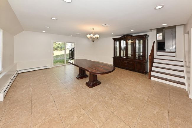 Unfurnished dining area featuring stairway, visible vents, baseboard heating, an inviting chandelier, and recessed lighting | Image 7