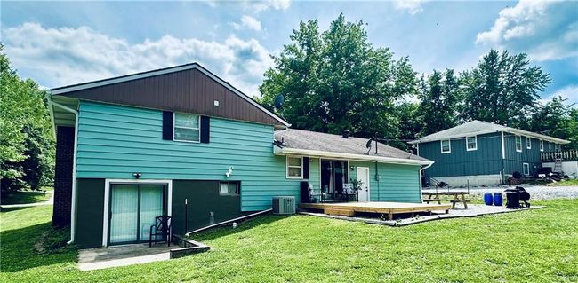 Rear view of property featuring a deck, central AC unit, and a yard | Image 25