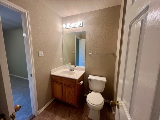 Half bathroom featuring a textured wall, vanity, and wood finished floors | Image 32