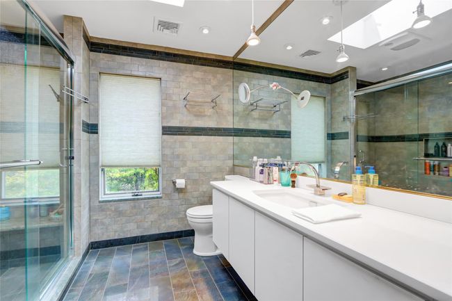 Bathroom featuring visible vents, a stall shower, tile walls, vanity, and a skylight | Image 14
