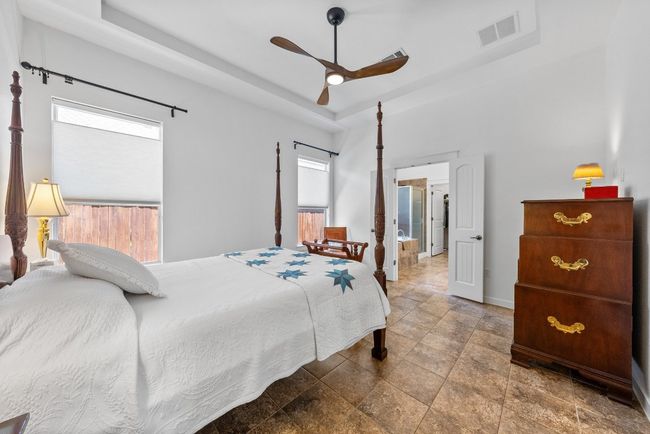 Bedroom featuring visible vents, baseboards, a raised ceiling, a ceiling fan, and stone finish floor | Image 16