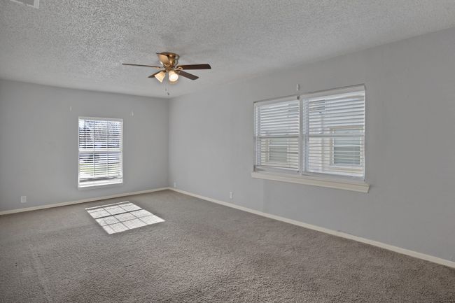 Spare room with ceiling fan, a textured ceiling, baseboards, and carpet | Image 10